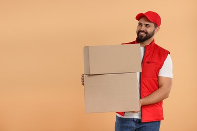 Photo of Happy young courier with parcels on light brown background. Space for text