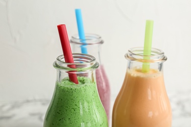 Bottles with healthy detox smoothies on light background, closeup