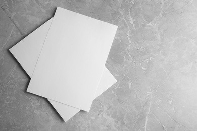 Photo of Blank paper sheets on light grey marble background, top view. Mock up for design