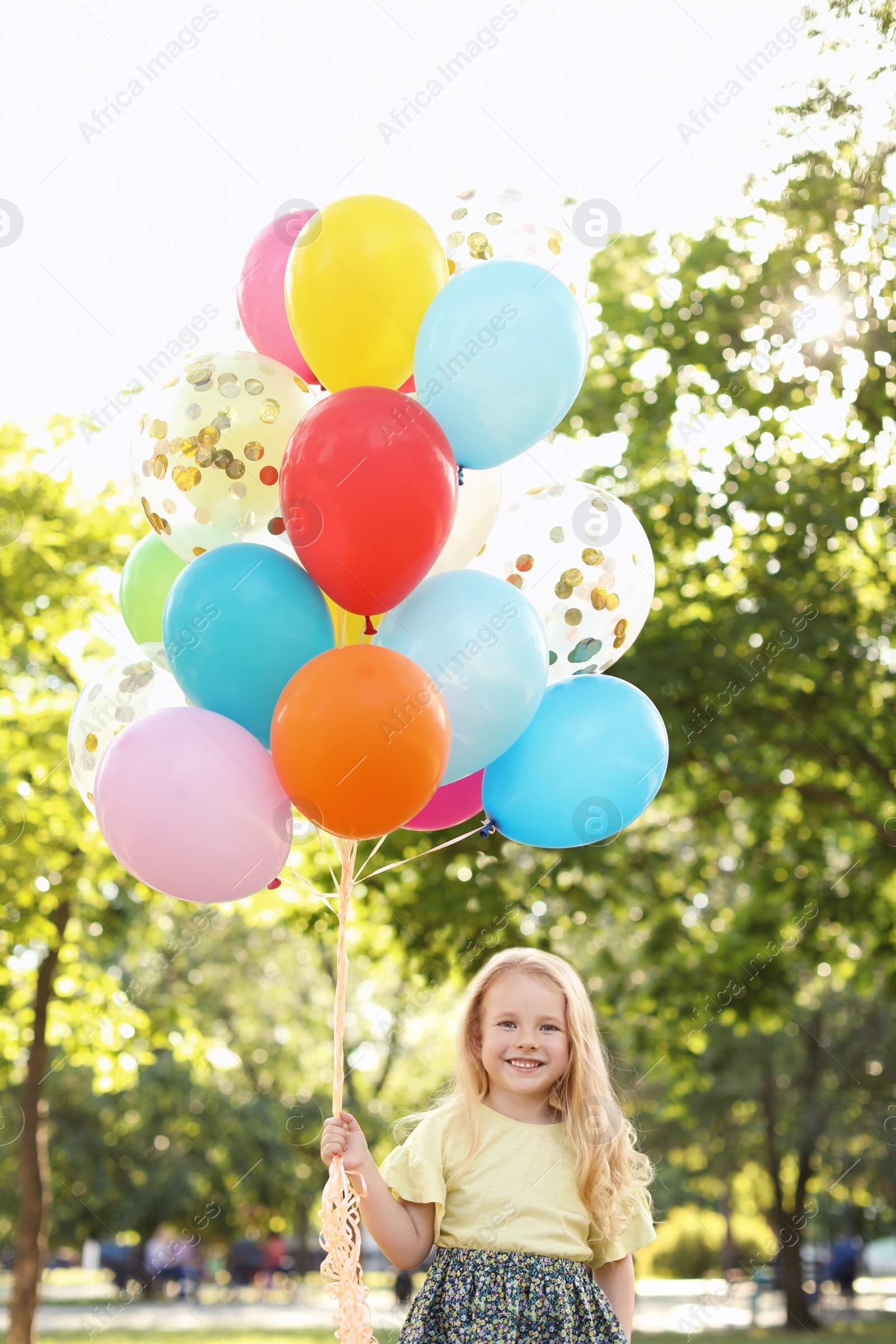 Photo of Cute little girl with colorful balloons outdoors on sunny day