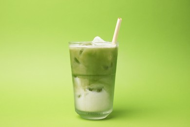 Photo of Glass of tasty iced matcha latte on light green background