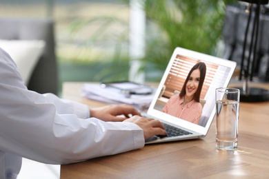 Doctor consulting patient online by video chat in medical office, closeup