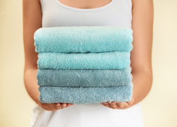 Photo of Woman holding fresh towels on beige background, closeup