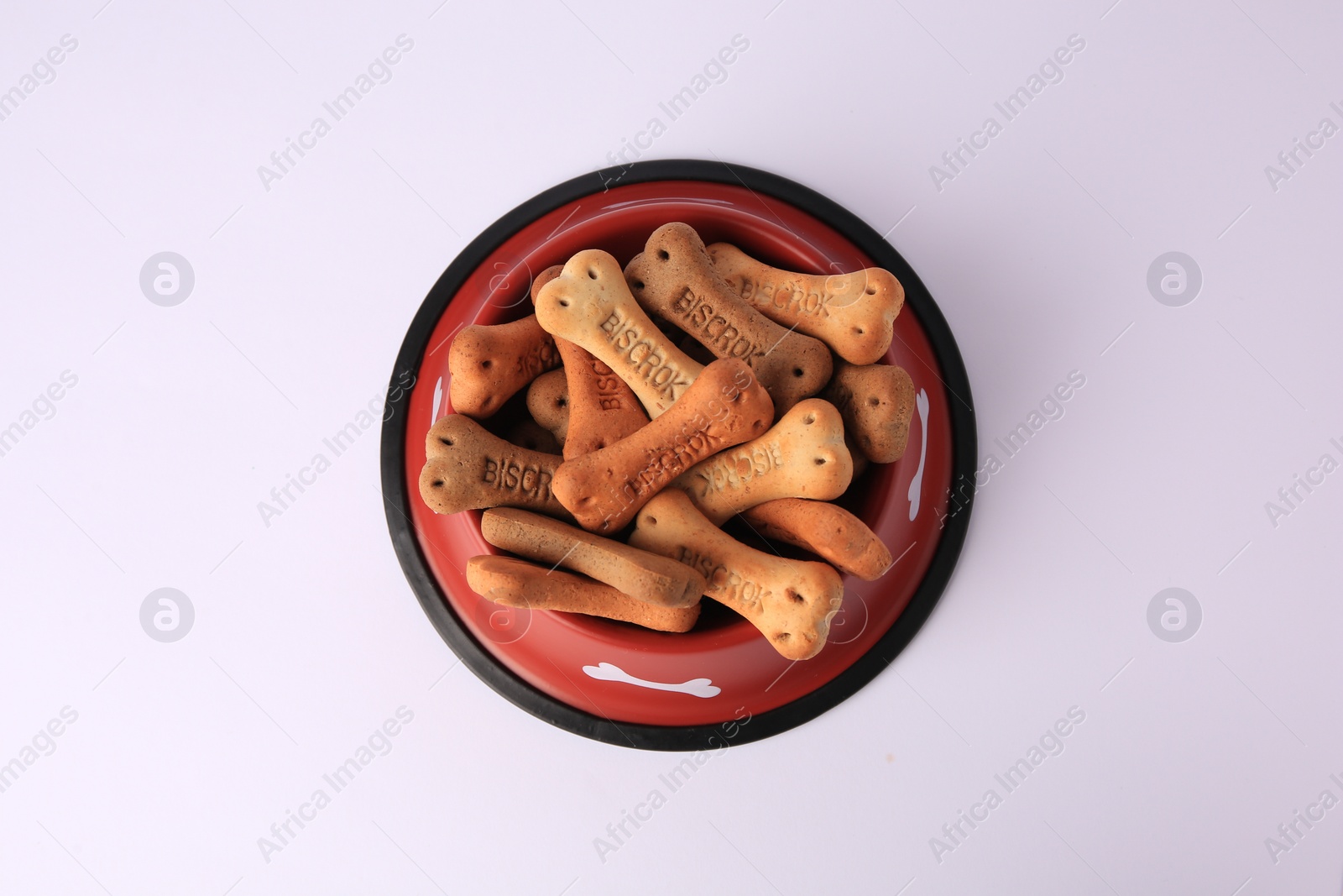 Photo of Bone shaped dog cookies in feeding bowl on white background, top view