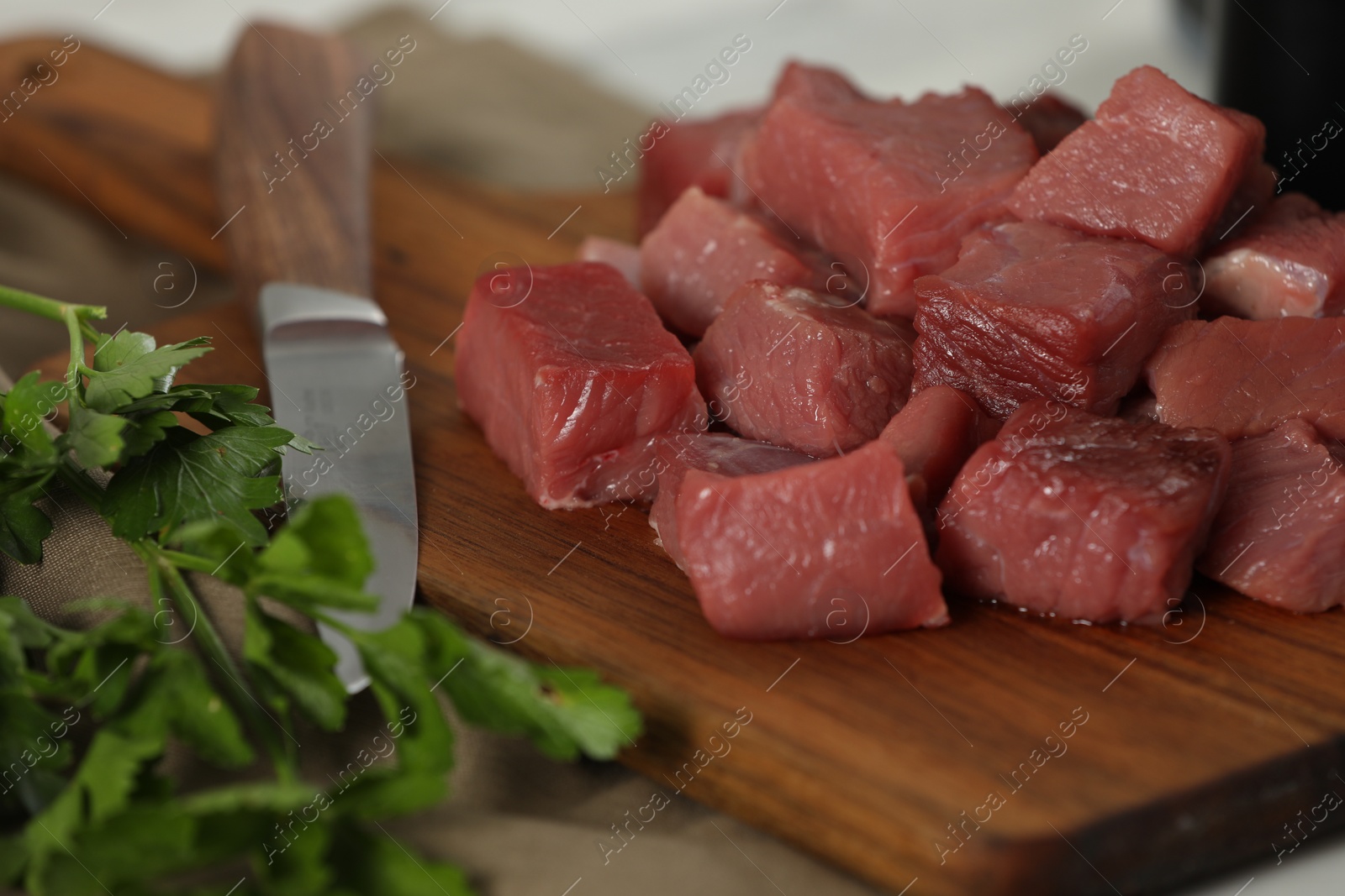 Photo of Pieces of raw beef and parsley on table, closeup