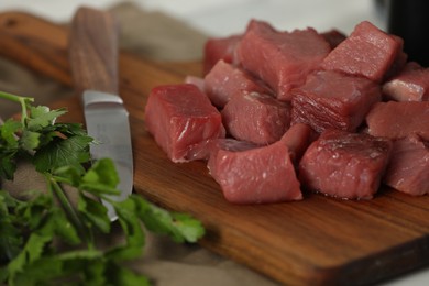 Pieces of raw beef and parsley on table, closeup