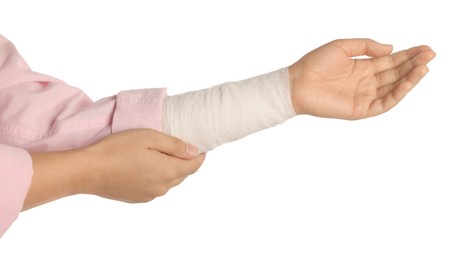 Woman with wrist wrapped in medical bandage on white background, closeup