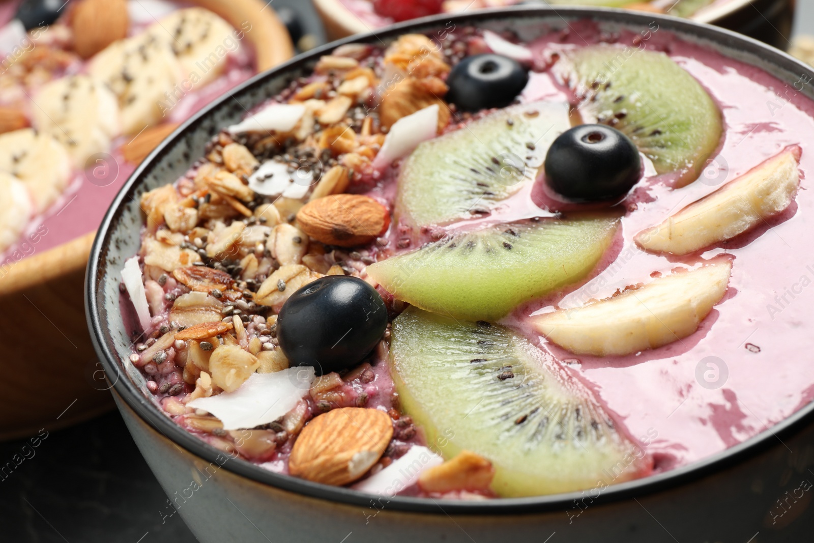 Photo of Delicious acai smoothie with granola and fruits in dessert bowl, closeup