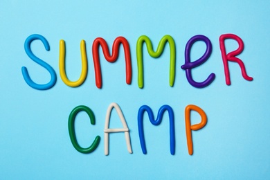 Text SUMMER CAMP made of modelling clay on color background, flat lay