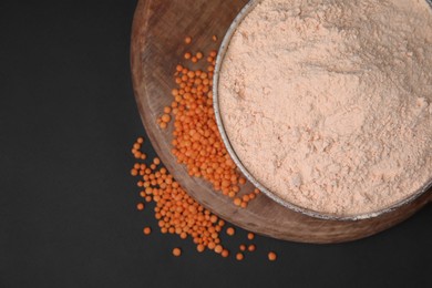 Photo of Bowl of lentil flour and seeds on dark table, top view. Space for text