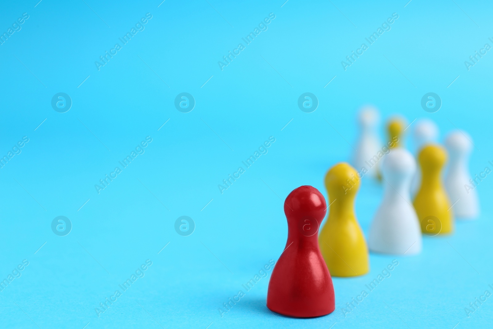 Photo of Red playing piece with following group on light blue background, space for text. Roles and responsibility concept