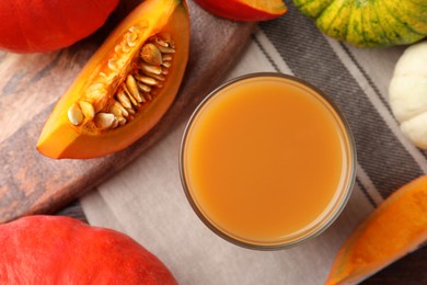 Photo of Tasty pumpkin juice in glass and different pumpkins on table, flat lay