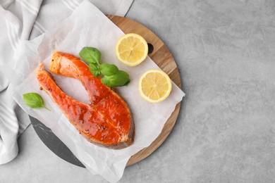 Photo of Fresh marinade, fish, lemon and basil on grey table, top view. Space for text