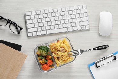 Photo of Container with tasty food, keyboard, mouse, notebooks and glasses on white wooden table, flat lay. Business lunch