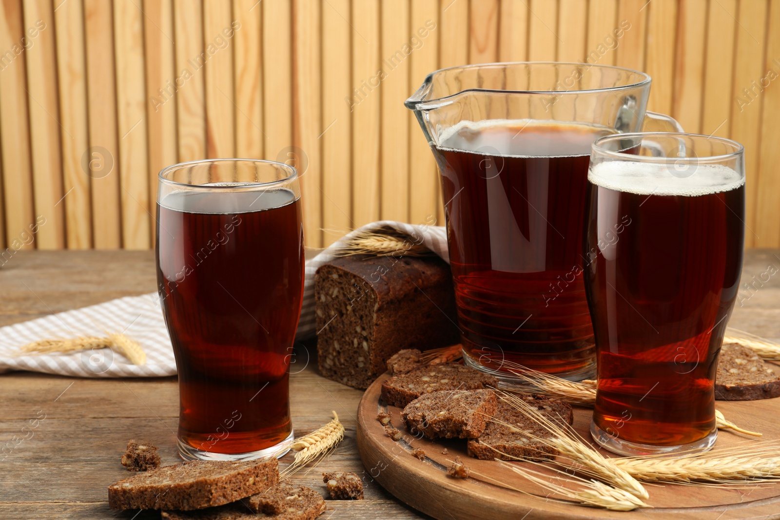 Photo of Delicious kvass, bread and spikes on wooden table