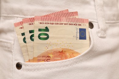 Photo of Euro banknotes in pocket of white jeans, closeup. Spending money