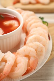 Photo of Tasty boiled shrimps with cocktail sauce, chili and parsley on light wooden table, closeup