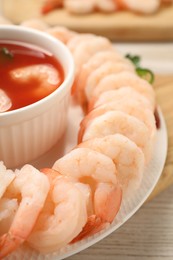 Tasty boiled shrimps with cocktail sauce, chili and parsley on light wooden table, closeup