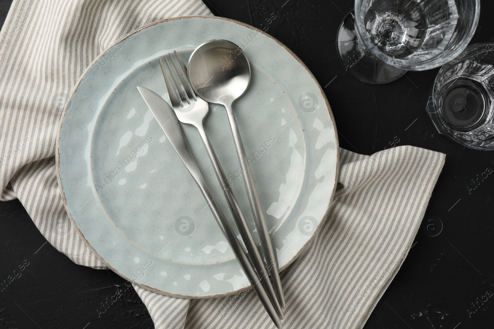 Photo of Stylish setting with cutlery, napkin and plate on dark table, flat lay