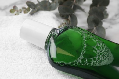Photo of Fresh mouthwash in bottle on white towel, closeup