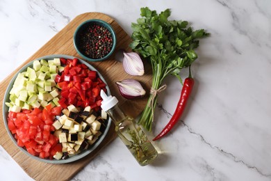Cooking delicious ratatouille. Fresh ripe vegetables and plate on white marble table, flat lay