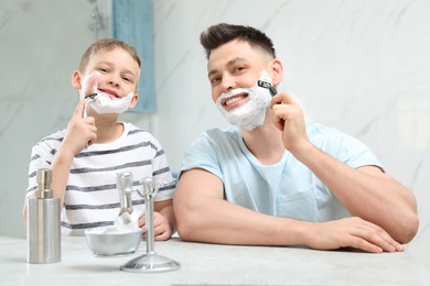 Photo of Dad shaving and son imitating him in bathroom
