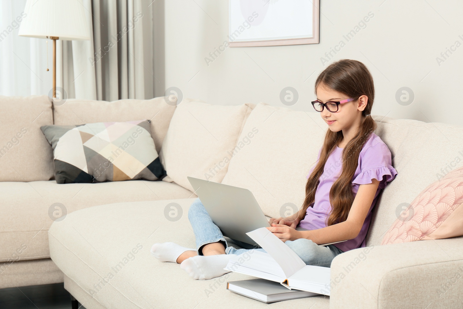 Photo of Girl with laptop and books on sofa at home