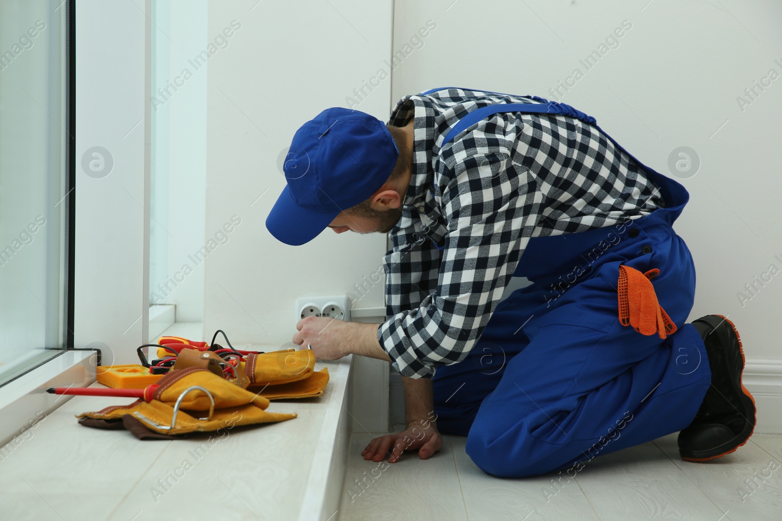 Photo of Professional male electrician repairing power socket indoors