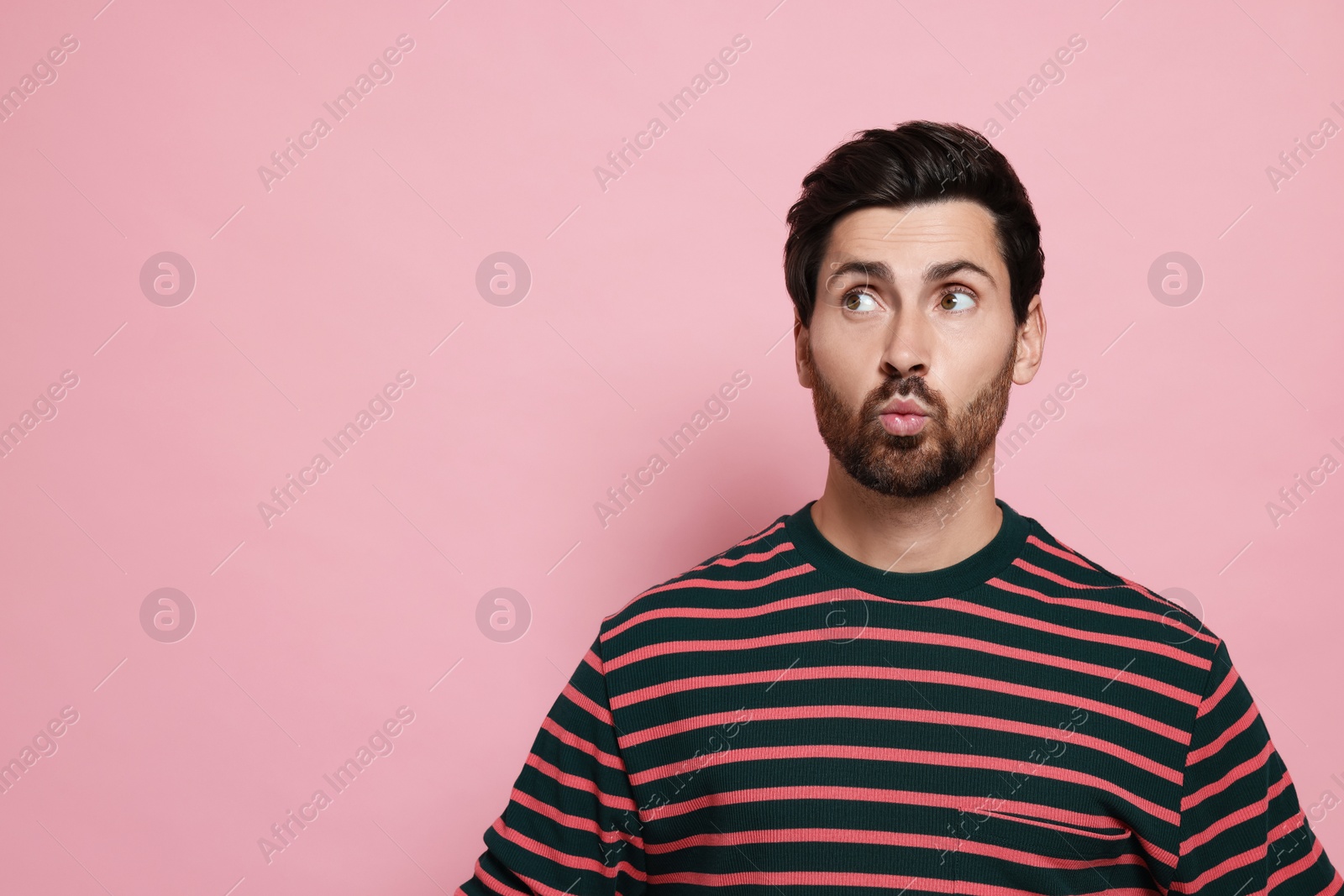 Photo of Handsome man blowing kiss on pink background. Space for text