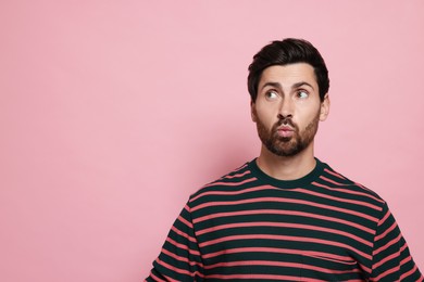 Handsome man blowing kiss on pink background. Space for text