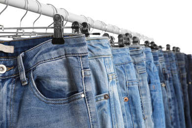 Photo of Rack with different jeans isolated on white, closeup