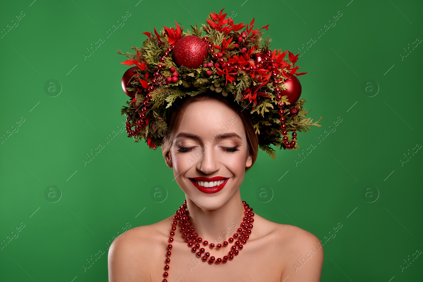 Photo of Beautiful young woman wearing Christmas wreath on green background