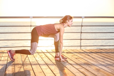 Photo of Fitness woman in position ready to run on pier in morning