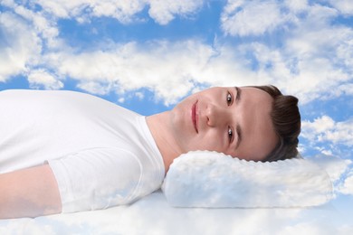 Man lying on orthopedic pillow against blue sky