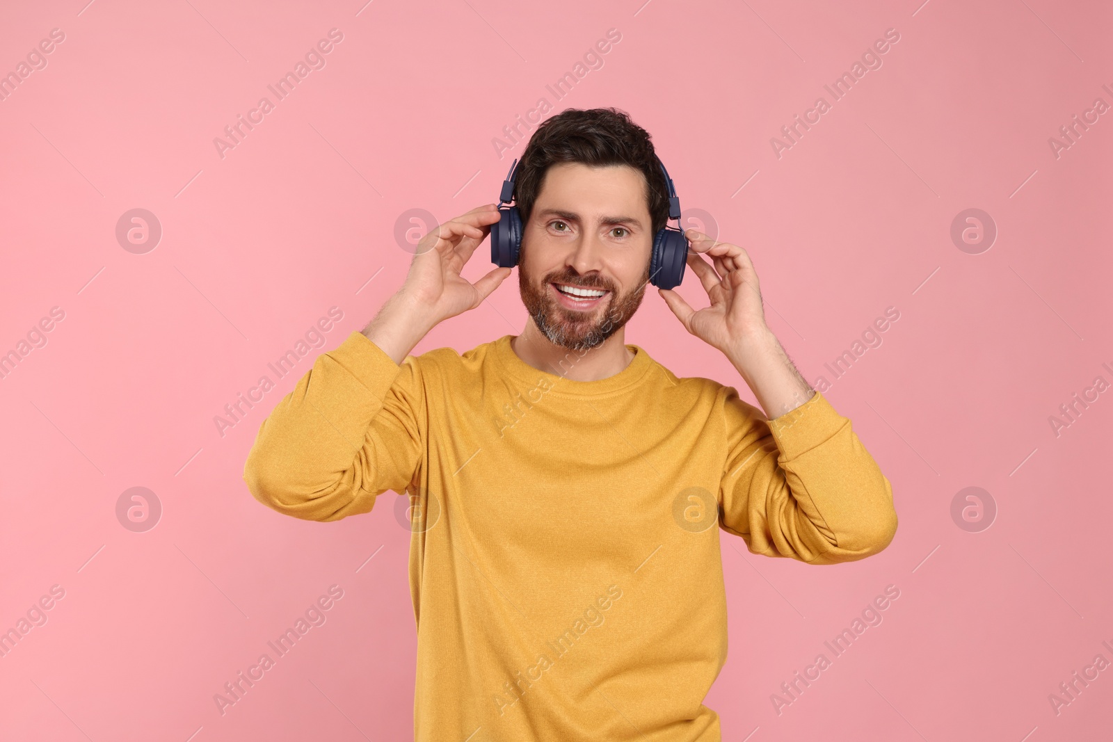 Photo of Happy man listening music with headphones on pink background