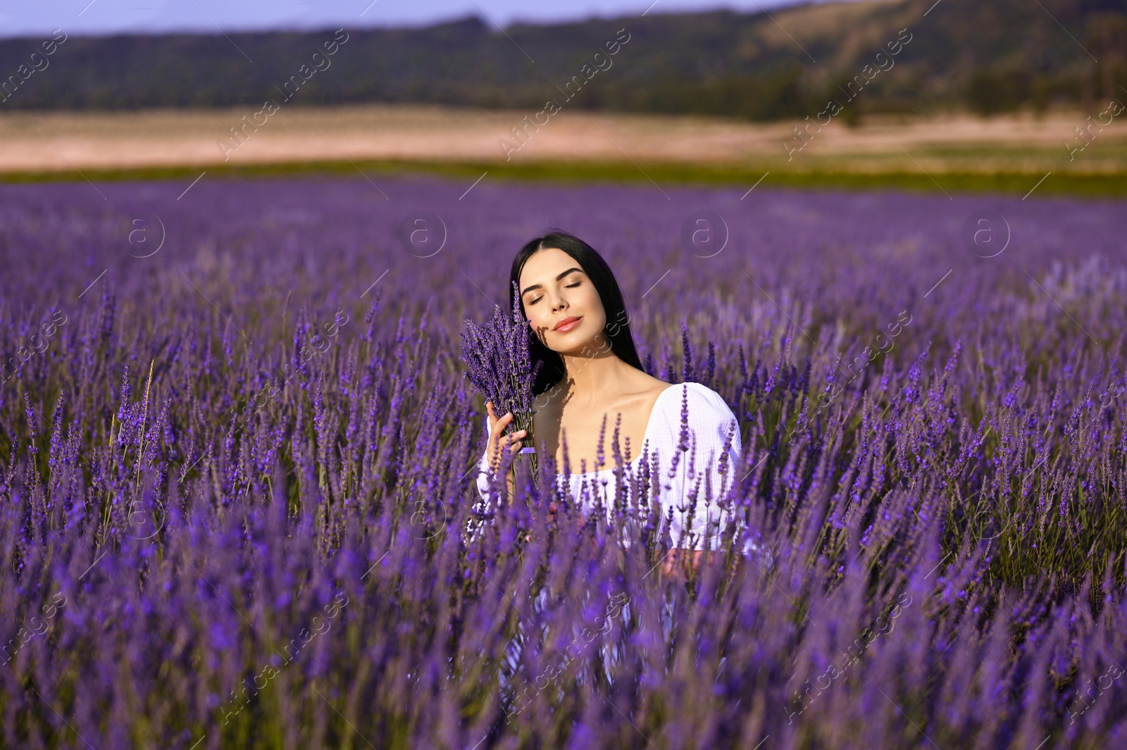 Photo of Beautiful young woman with bouquet in lavender field