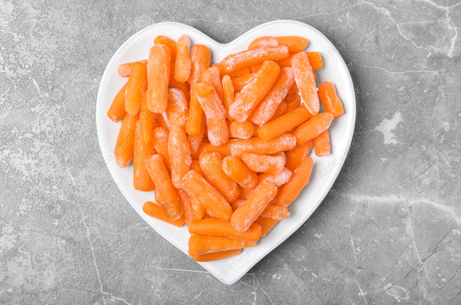 Photo of Plate with frozen carrots on grey background, top view. Vegetable preservation