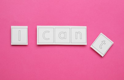 Motivation concept. Changing phrase from I Can't into I Can by removing paper with letter T on pink background, top view