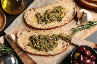 Photo of Tasty bruschettas with pesto on black table, flat lay