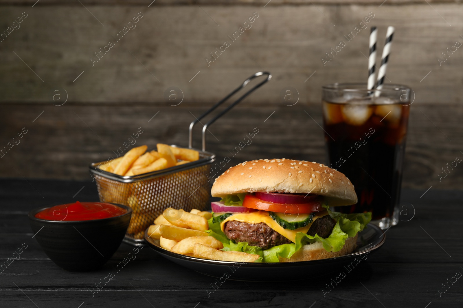 Photo of Delicious burger, soda drink and french fries served on black table