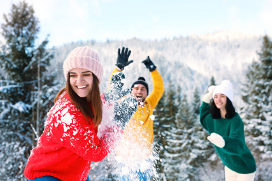 Happy friends playing snowballs outdoors. Winter vacation