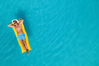 Image of Happy man with inflatable mattress in swimming pool, top view and space for text. Summer vacation