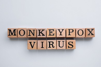 Photo of Words Monkeypox Virus made of wooden cubes on light background, top view