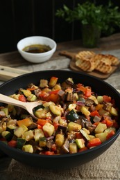 Photo of Delicious ratatouille and spoon in baking dish on table