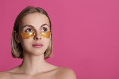 Photo of Beautiful young woman with under eye patches on pink background, space for text