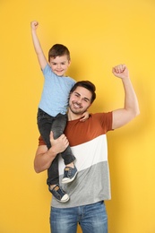 Portrait of emotional dad and his son on color background