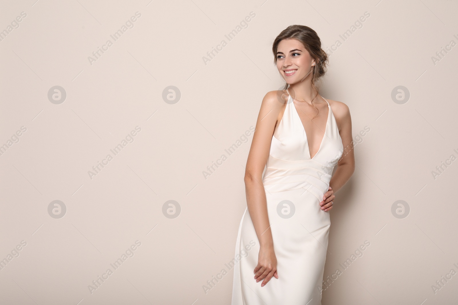 Photo of Young bride wearing beautiful wedding dress on beige background. Space for text