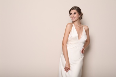 Photo of Young bride wearing beautiful wedding dress on beige background. Space for text