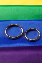 Wedding rings on rainbow LGBT flag, closeup