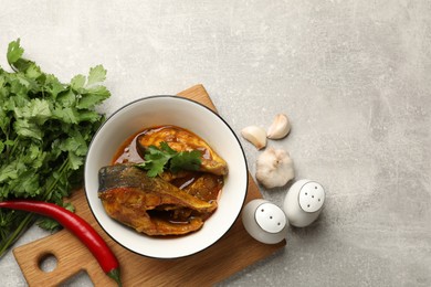 Photo of Tasty fish curry and ingredients on light grey table, flat lay. Space for text. Indian cuisine